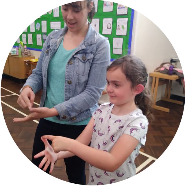 A child and volunteer practicing Makaton signs