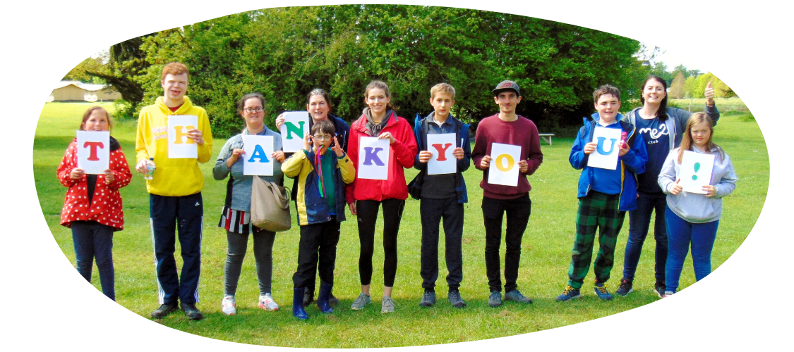 A group of teenagers, each holding up signs with letters to spell "thank you".